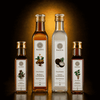 Four glass bottles of Kaizer oils with gold caps, arranged on a reflective black surface against a warm glowing background.