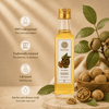 A bottle of Kashmiri Walnut Oil with a bowl of walnuts. The oil appears clear and is displayed against a warm background.