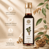 A bottle of Kaizer Malkangani Oil stands on a wooden surface with decorative leaves, berries, and a small bowl of seeds. Text on the left highlights key product benefits: 100% cold-pressed, traditionally extracted, lab tested, and traditionally used for scalp massage.