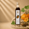 A bottle of Kaizer pumpkin seed oil stands on a wooden board with pumpkins, leaves, and a bowl of pumpkin seeds around it. 